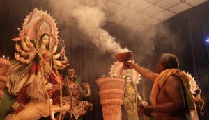 Priest performing aarti with a dhunuchi before a Durga idol during Durga Puja in North Bengal